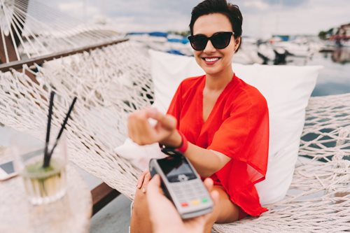 Woman at beach cafe paying with smartwatch